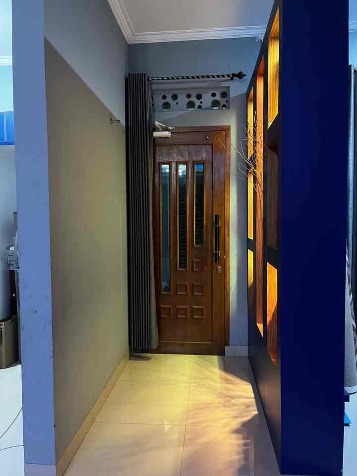Modern entrance space with navy wall and wood-tone door, featuring warm lighting and blackout curtain creating a cozy atmosphere