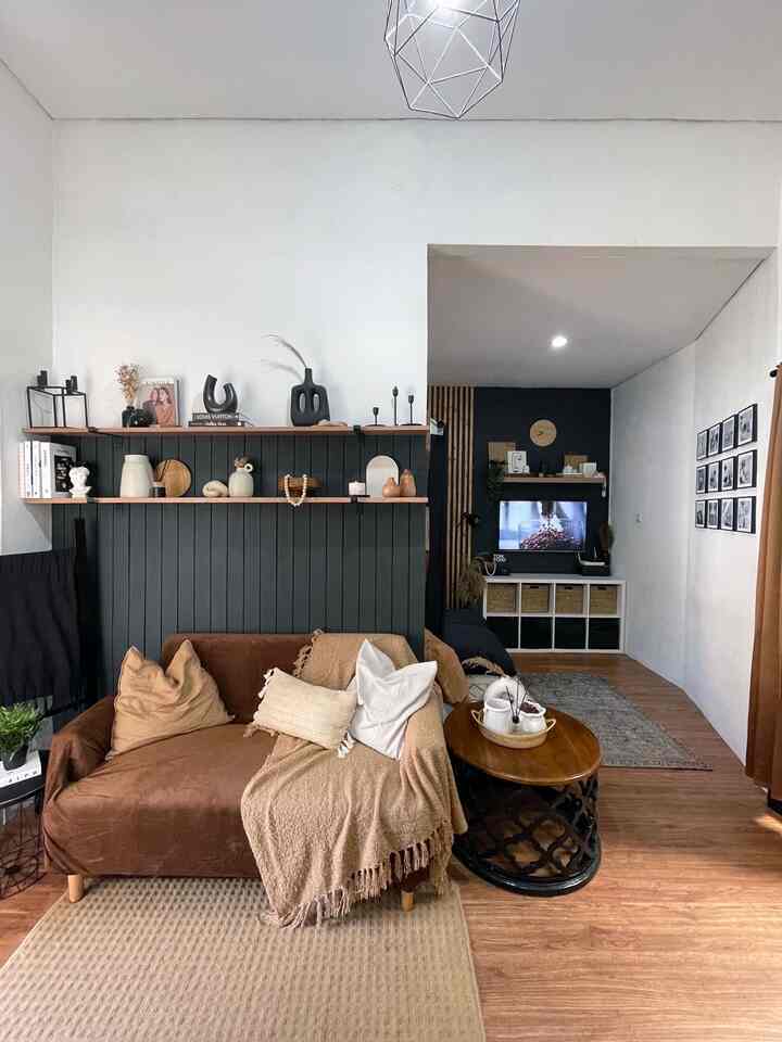 Living room with white walls and wood tones, featuring a brown sofa, coffee table, TV stand, and decorative shelves creating a cozy atmosphere