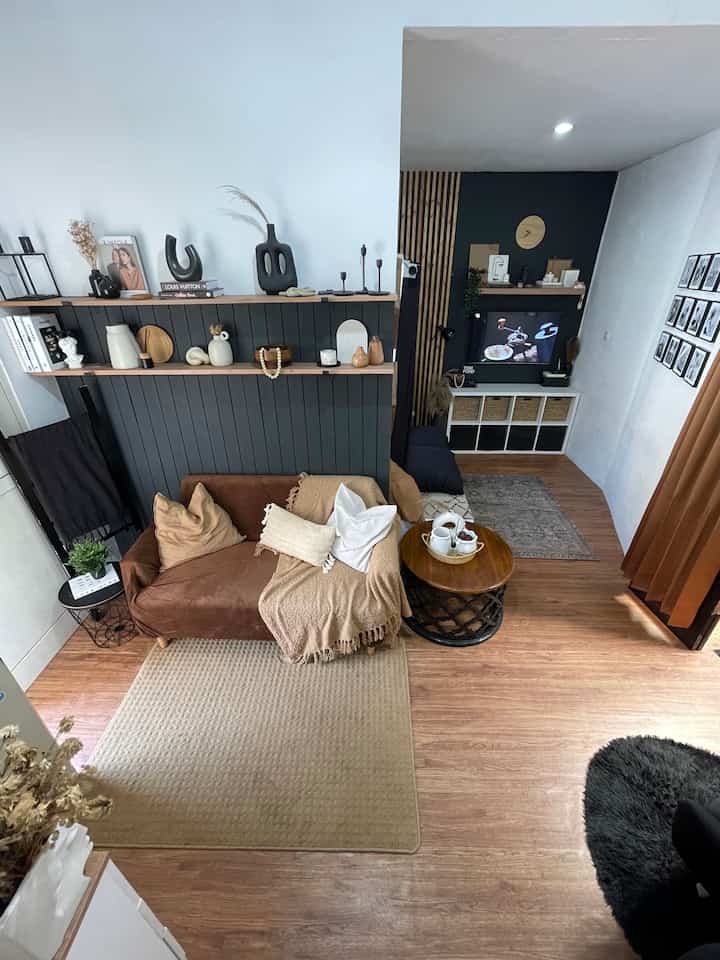 Compact living room with black and wood tones, featuring a brown sofa and round coffee table creating a cozy atmosphere