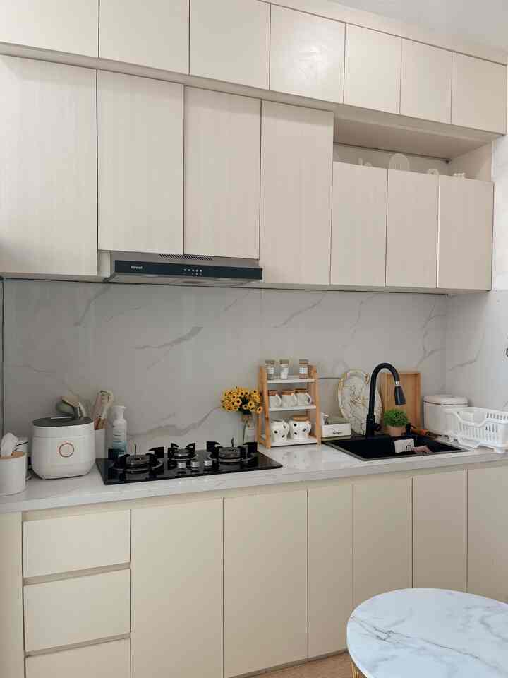 Modern white kitchen featuring a black cooktop and sink with clean and organized aesthetic