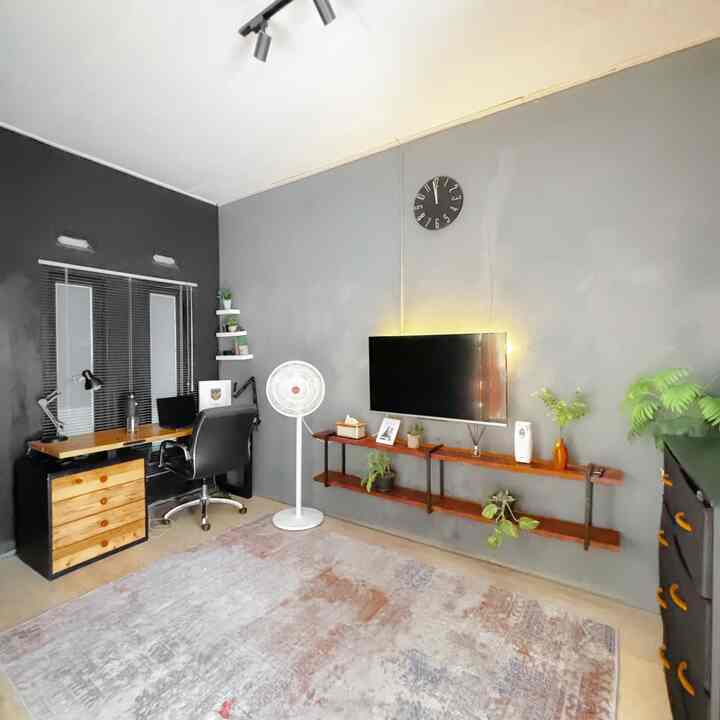 Gray and black toned home office space featuring a desk, office chair, wall-mounted TV, and carpet with modern interior design