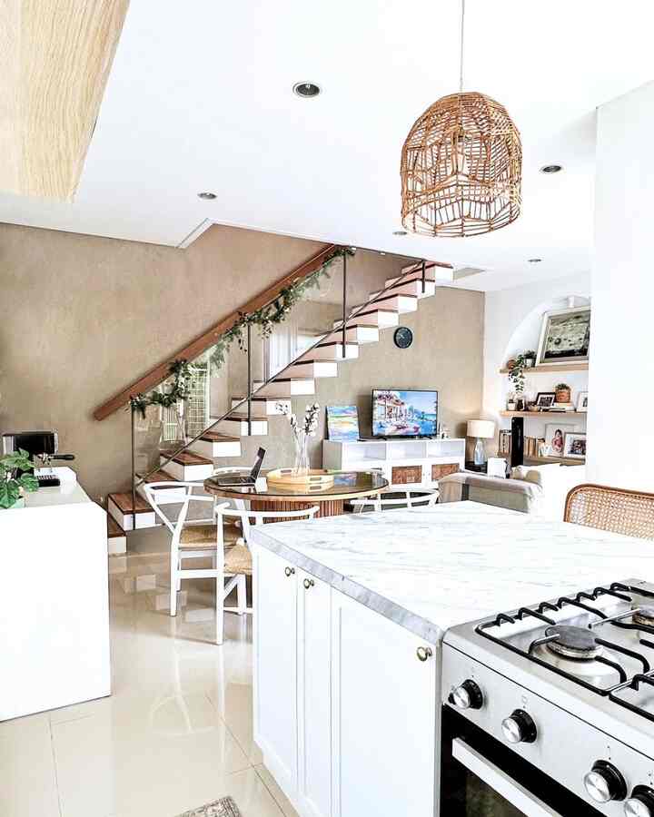 White and natural-toned kitchen and living room featuring stairs and rattan pendant light with a cozy atmosphere