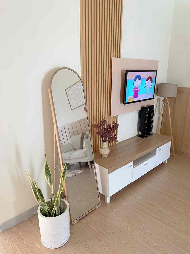 Bright natural-tone living room featuring white walls, wooden TV stand, floor lamp, and large standing mirror with clean design