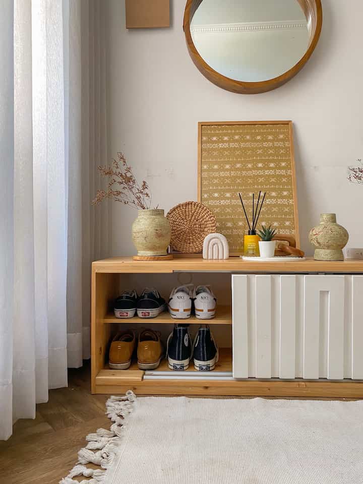 Beige and wood tone entrance featuring a shoe cabinet with vases and diffuser, creating a cozy atmosphere
