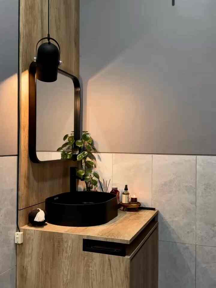 Natural-toned bathroom vanity with brown wood finishes, black sink, and mirror creating a cozy atmosphere