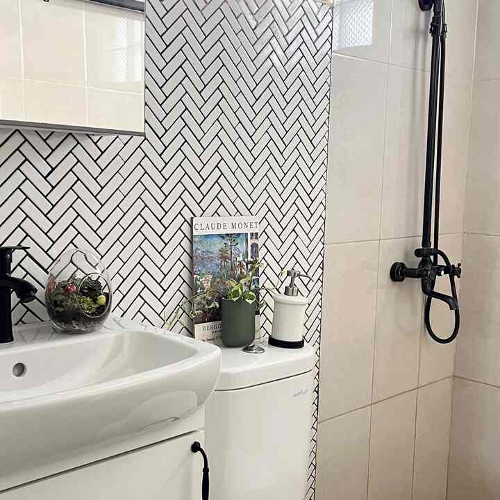 White and black toned bathroom featuring a sink, toilet topped with plant and Claude Monet art print, creating a clean atmosphere