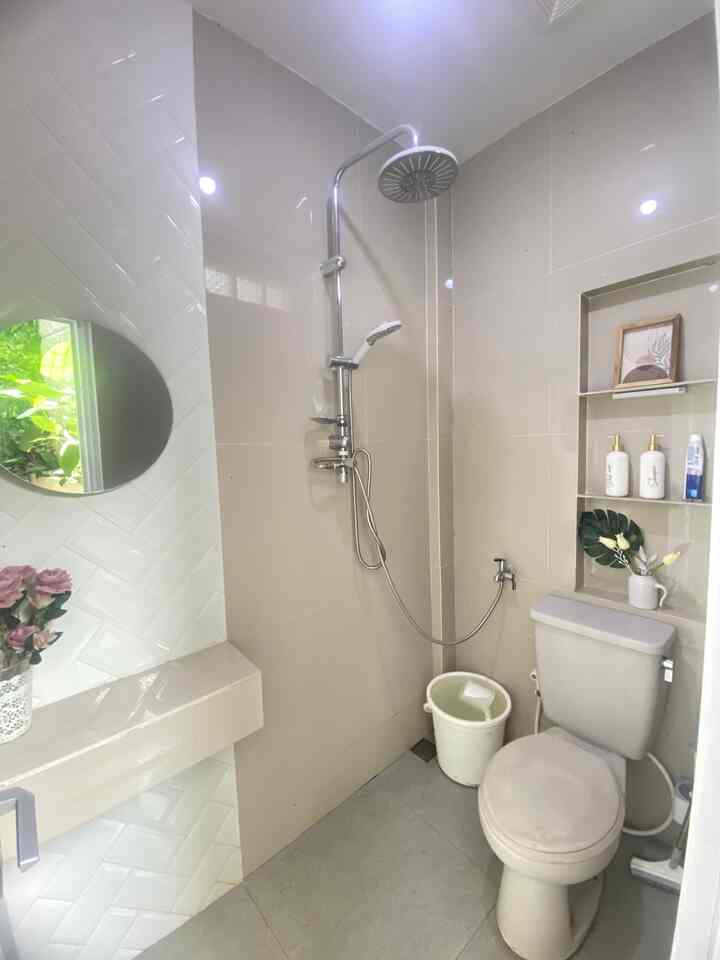 Beige and gray toned compact restroom featuring a simple functional shower and toilet setup