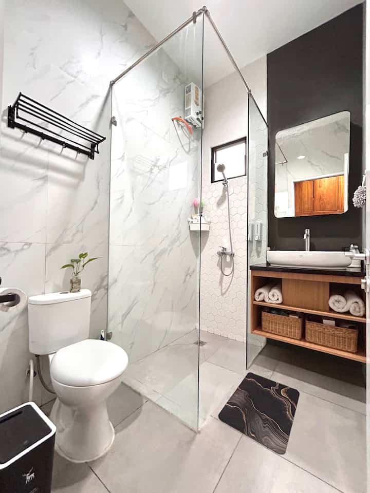 Compact bathroom in white and black tones featuring wooden cabinet and rattan baskets with a simple design