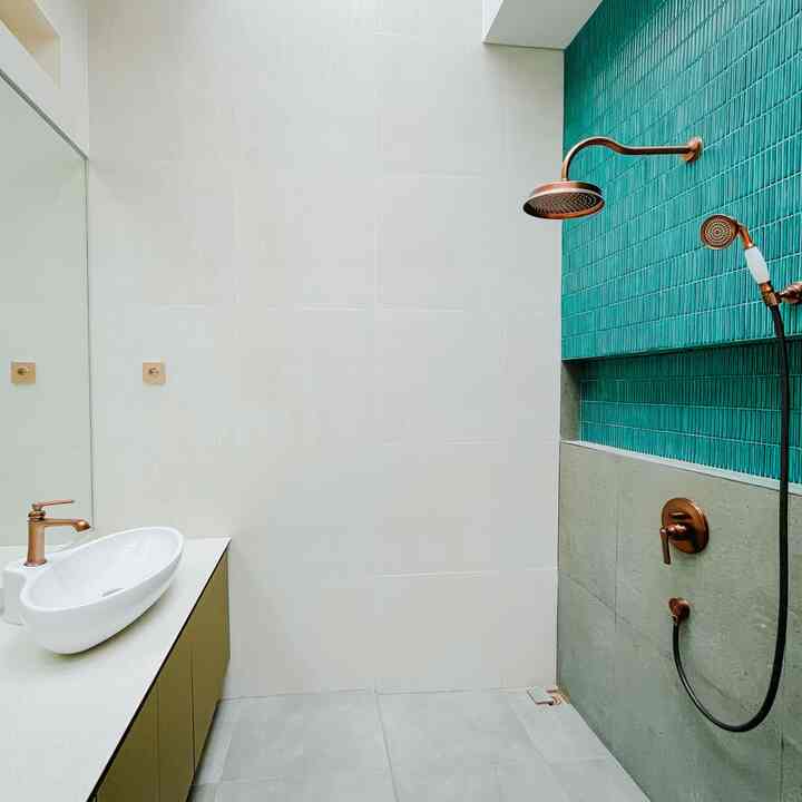 SFhaus has 4 bathrooms. The concept, material, color palette, and sanitary are not differentiated to be cohesive with the overall house that carries the colonial art deco theme, but there are still characters and colors that are highlighted in each bathroom. Master & Kid bathroom = green. Guest bathroom = dark red. ART bathroom = creamy white. 

The SFhaus master bathroom measures 2.4 x 2.1 m, not big and does not use a bathtub because we are not the type who linger in the bathroom. The master bathroom is designed with a his-her sink and a wall-to-wall mirror measuring 2.4 x 1.8 m. The highlighted color in the master bathroom is green, on the mosaic tiling and vanity. 

All of our bathrooms are designed with a tropical bioclimatic concept that optimizes energy saving, smooth air circulation, optimal lighting, passive cross ventilation (air flows even when the door is closed). This creates a bright, non-humid, and odorless bathroom without an exhaust fan. 

The roof is fitted with a ventilated skylight with a 40 cm high opening using steel mosquito nets to prevent insects from entering, plus bengkirai wood lattices. The walls have air vents. This concept optimizes negative pressure, stacked effect, and passive cross ventilation so that it does not require an exhaust fan. Air pollution only takes about 30 seconds to be sucked out, checked using colored smoke. 

All bathrooms use PVC vanities for maximum economic life. Lots of storage for cleaning tools, personal care, rags and towels. The tabletop uses the same sintered stone as the kitchen. Using a solar water heater instead of a high-power electric water heater, so that the ceiling looks clean and energy efficient. 

If you pay attention, we do not use glass dividers, because of experience in previous homes, it is very difficult to clean glass from water mold every weekend. The shower position has been set optimally so that it splashes too much into the toilet. 

#BathroomCeramics #KeramikMosaic #Wastafel #PintuKamarMandi #CatKamarMandi #WarnaKamarMandi #DindingKamarMandi #KeramikDinding #KeramikLantai #Solarwaterheater #RenovasiKamarmandi #BathroomMakeOver #InspirasiKamarMandi