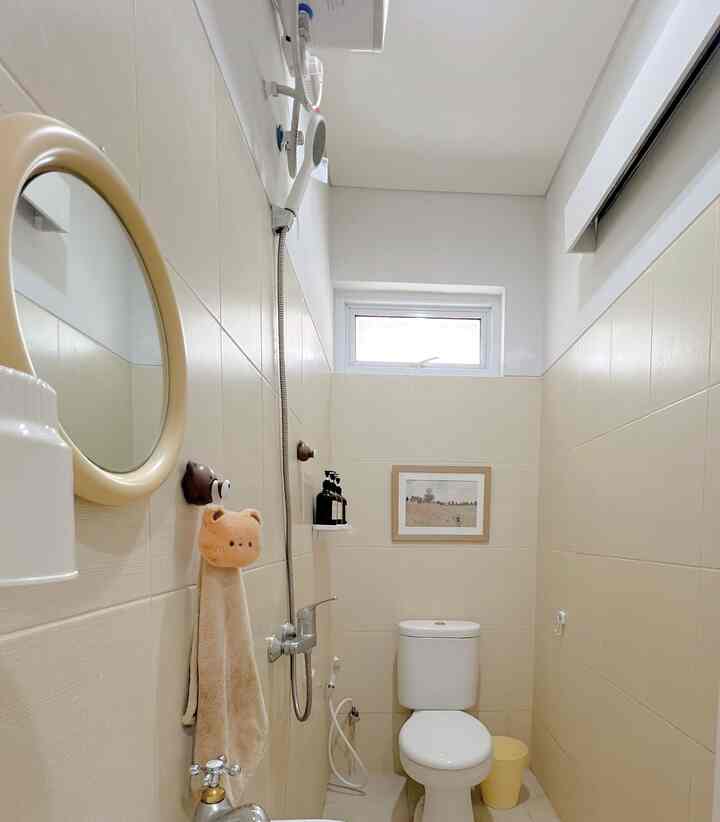 White and beige toned bathroom with centrally positioned toilet and shower in a compact layout