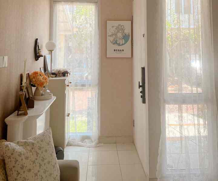 Entrance space in white and beige tones featuring lace curtains and wall decor, with a clean, cozy, and naturally lit atmosphere