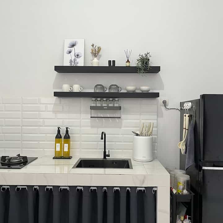 A modern kitchen in white and black tones, featuring wall shelves and neat storage ideas for a clean look