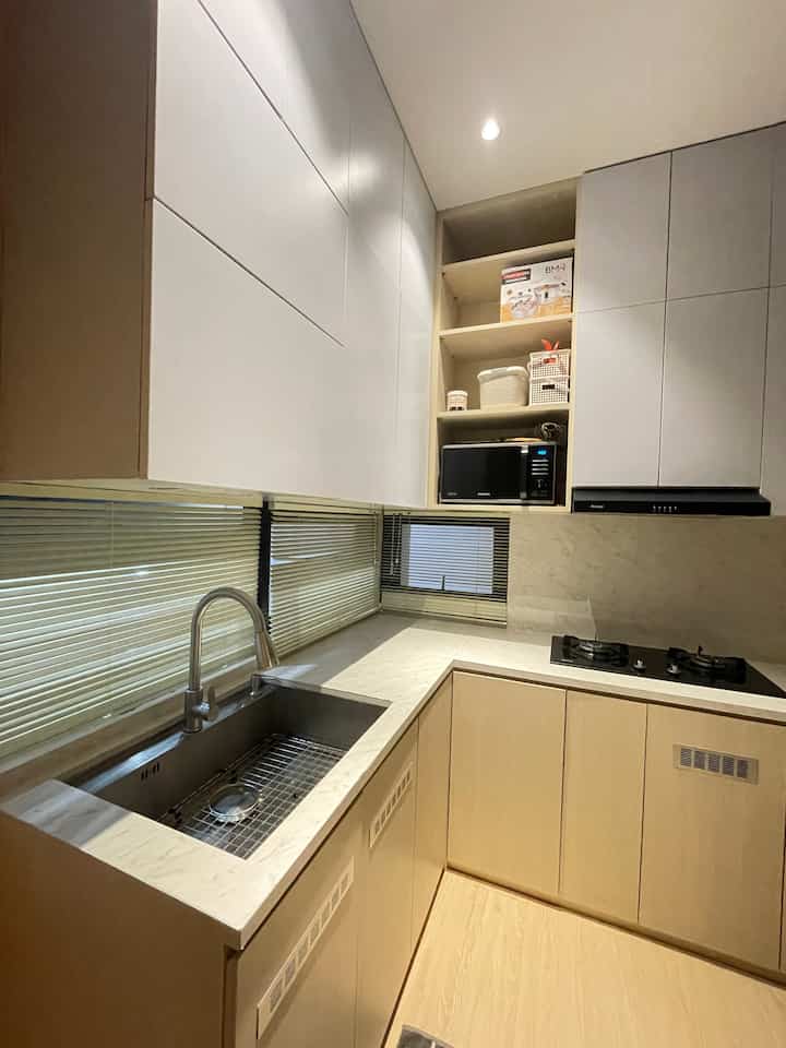 Beige lower cabinets and white upper cabinets in kitchen, featuring stainless steel sink and gas stove in practical setup