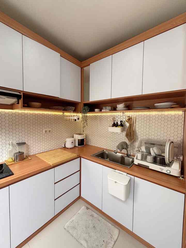 Natural tone and wood-accented clean L-shaped kitchen featuring organized kitchenware and cabinetry
