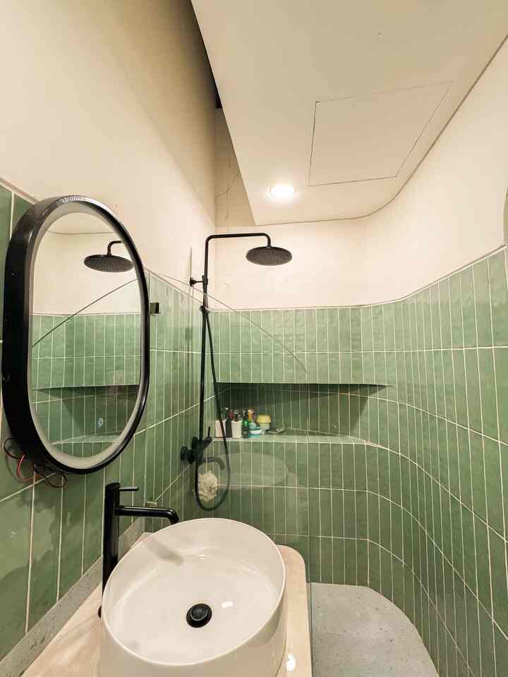 Green tiled, white washbasin bathroom in a narrow, vertically elongated modern space