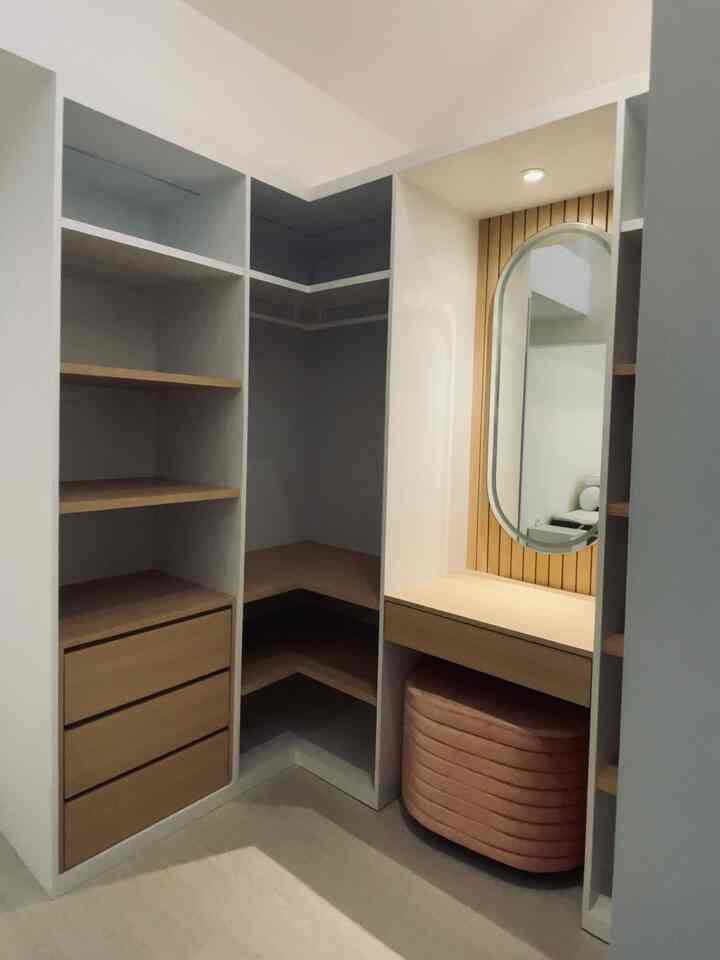 Natural-toned walk-in closet featuring built-in closet and vanity with an oval mirror, creating a cozy and neat atmosphere
