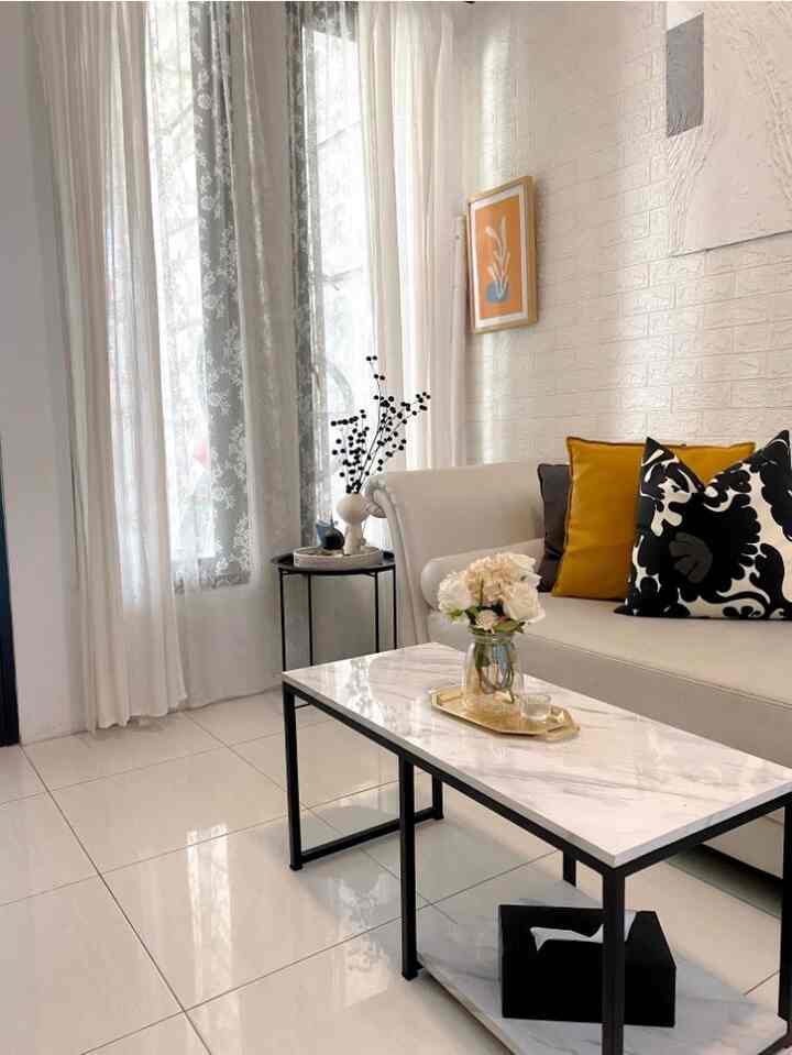 Bright white and gold toned living room featuring a modern sofa, marble coffee table, decorative cushions, and a gold tray with a cozy atmosphere