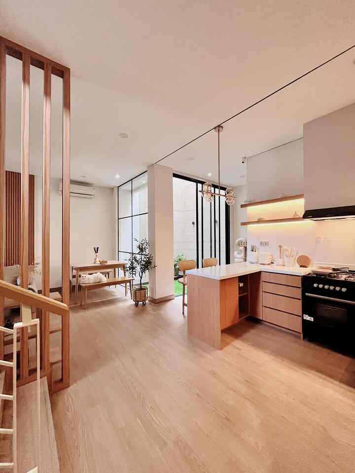 Light brown wood tone natural style open kitchen and dining room with indoor garden and pendant lighting creating harmonious space