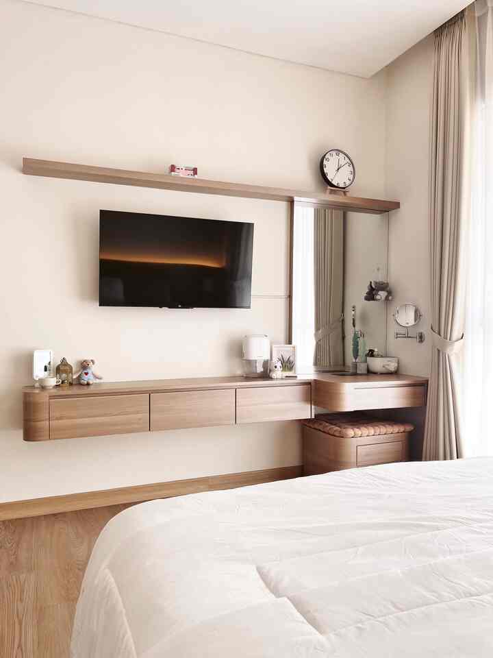 Natural tone bedroom featuring wall-mounted wooden shelf and desk, with white bedspread in a bright setting