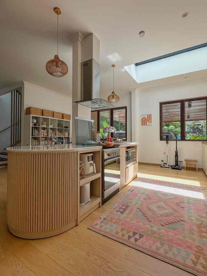 Bright white walls and wood tone kitchen in a bohemian-style kitchen space featuring a central island and carpet