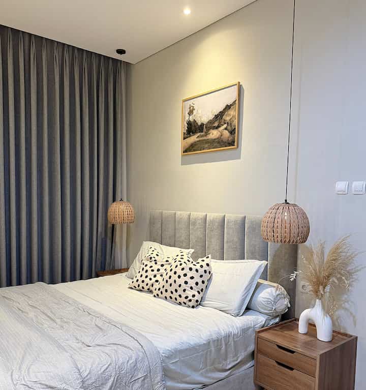 White and brown toned bedroom featuring a plush bed at center with rattan pendant lights on both sides creating a cozy atmosphere