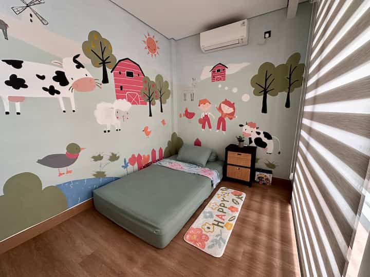 Kamar mungil tapi tetap nyaman dan playful! 🌿🎨

Ukurannya cuma 2.2 x 3 meter, tapi tetap terasa lega dan nyaman! Kasur tanpa dipan ternyata justru bikin ruang lebih fleksibel dan aman buat si kecil (padahal sih belum ada budget untuk beli dipan). Ditambah mural peternakan yang bikin suasana makin ceria, kayak ada di dunia dongeng sendiri! 🐄🌞

🛏 Tips bikin kamar kecil tetap cozy:
✔ Pilih warna soft & netral – Warna dinding hijau pastel bikin kamar terasa tenang dan nggak sumpek.
✔ Gunakan rak terbuka – Biar buku dan mainan tetap rapi tanpa bikin kamar terasa penuh.
✔ Pakai rainbow blind biar lebih praktis – Dibanding curtain, rainbow blind lebih simpel, nggak gampang jadi sarang debu, dan tetap nyaman buat anak kecil.

🌟 Kamar anak harus fun & nyaman! Dengan dekorasi simpel tapi penuh karakter, anak bisa tidur nyenyak dan menikmati ruangnya sendiri. Siapa yang juga suka kamar dengan mural seperti ini? ✨💛

#BedroomStyling #InspirasiKamar #KamarTidurNyaman #DekorasiKamarAnak #KamarAnakEstetik #KamarAnakPerempuan #KamarAnakMinimalis #IdeDekorasiKamar #HomeInspiration #ParentingTips #KamarMungil 