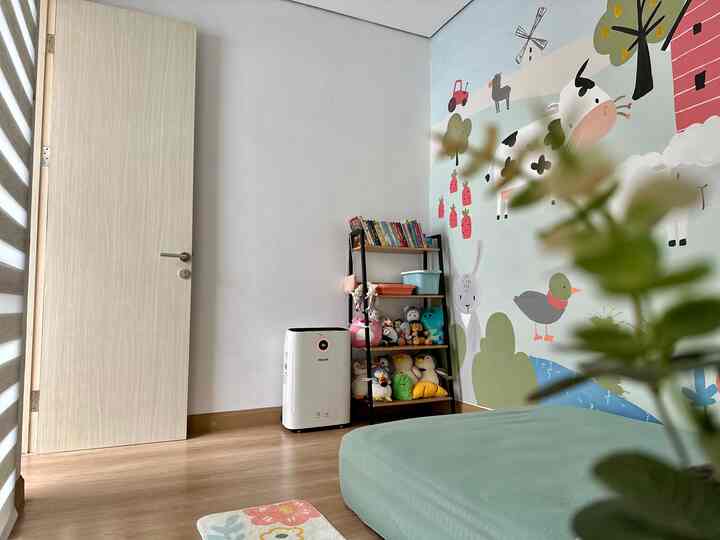 Children's room with light brown flooring, playful wallpaper, and a toy storage rack