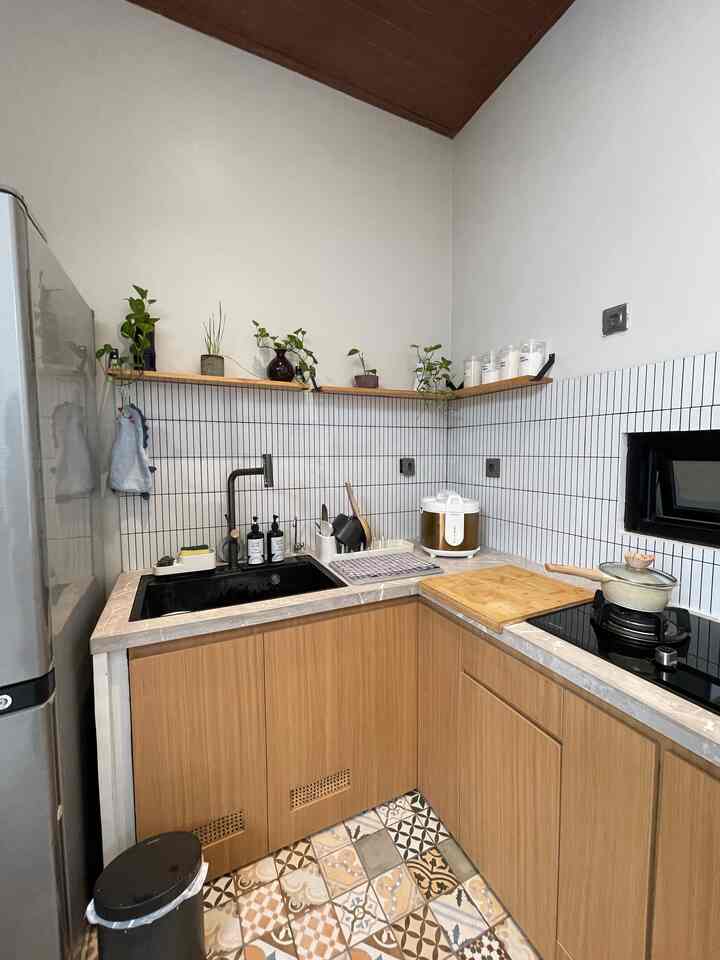Natural wood-tone and white tile kitchen featuring organized kitchen utensils and plants in a clean, compact space