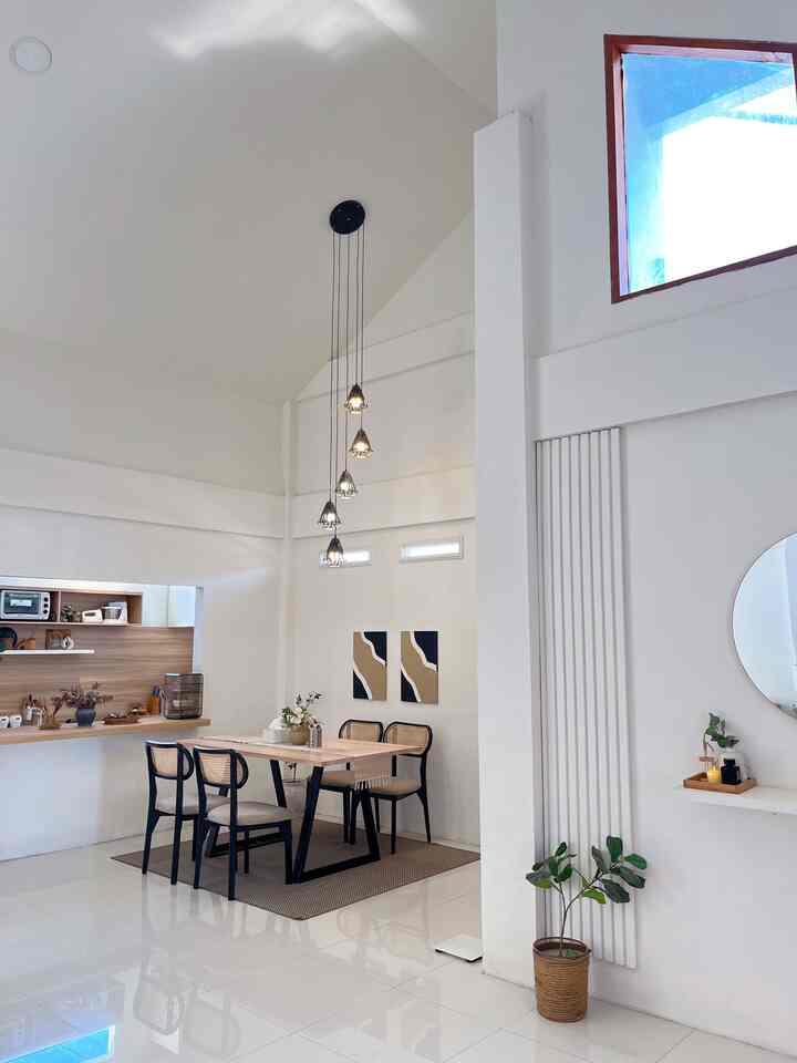 White and brown toned dining room featuring a dining table and pendant lights in a simple and natural space