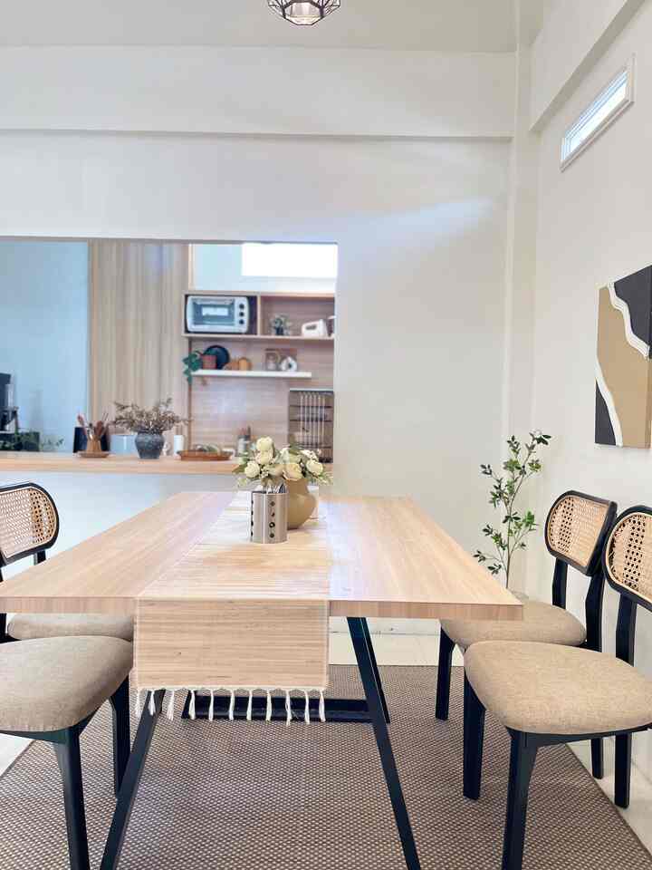 Natural color and wood tone dining room featuring a wooden dining table with rattan-back chairs in a neat setting