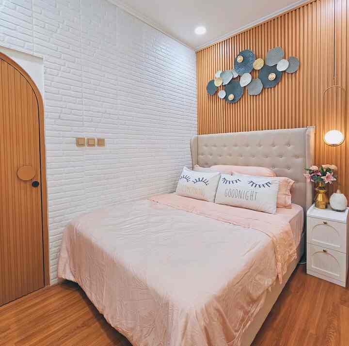 Cozy bedroom featuring bright pink bedding, beige headboard, and warm wooden tone walls