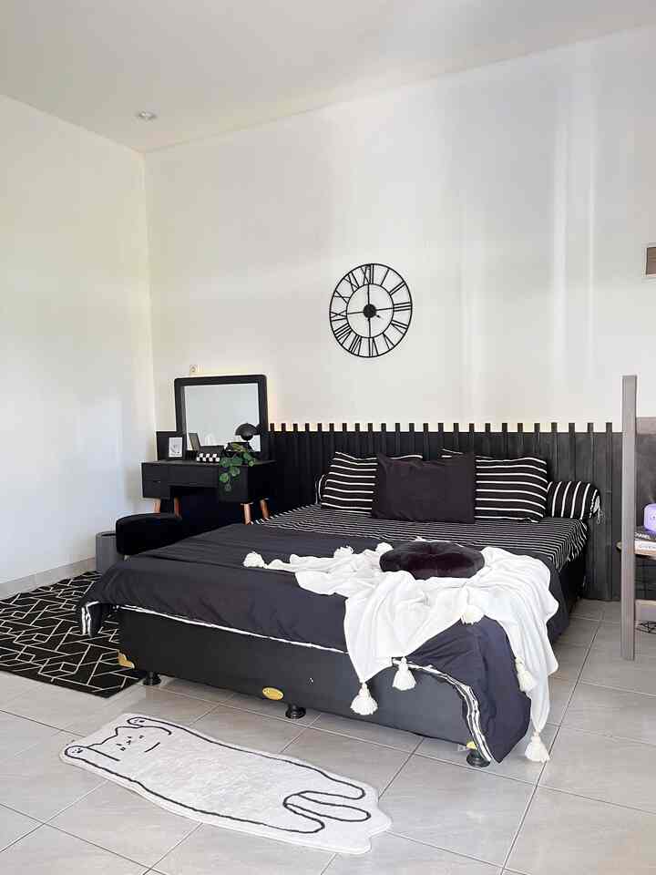 Modern compact bedroom with black bed and striped bedding set against white walls and floor