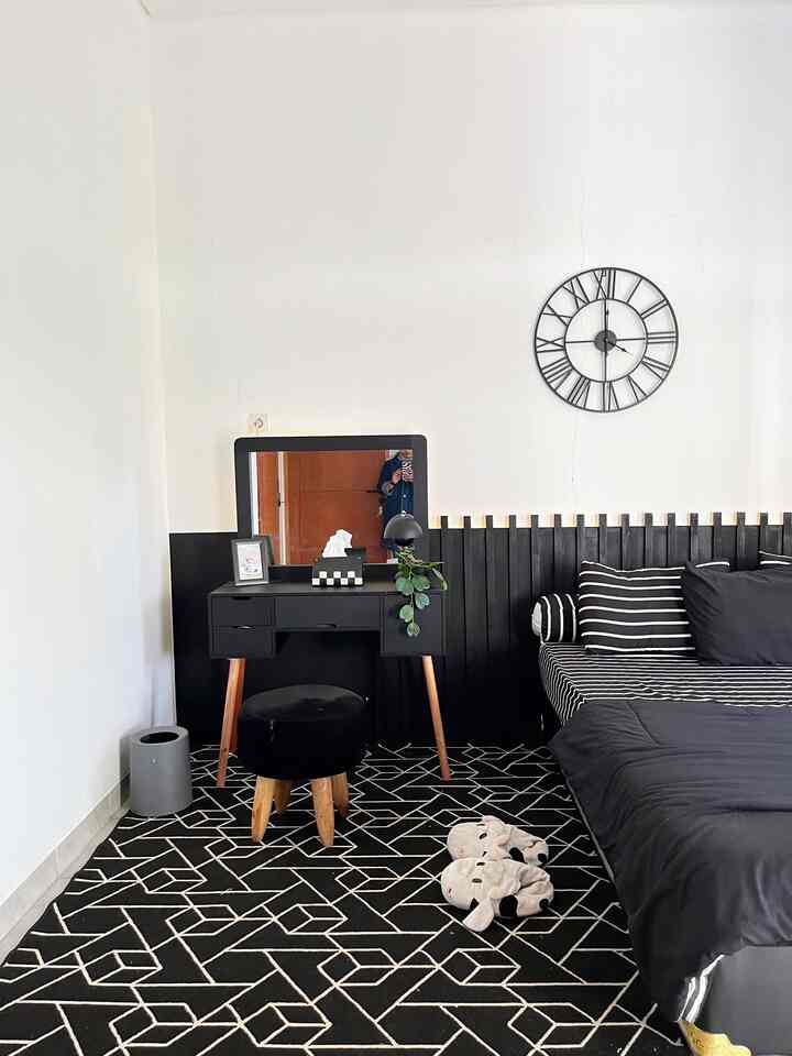 White-walled bedroom with black furniture and large geometric patterned carpet