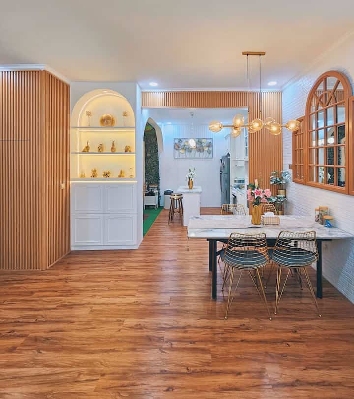 Wood tone and gold accented open kitchen and dining room featuring wall panels and pendant lighting in Japandi style