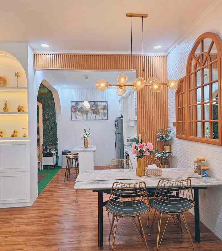 Dining room with wood tone walls and floor, featuring gold pendant lighting