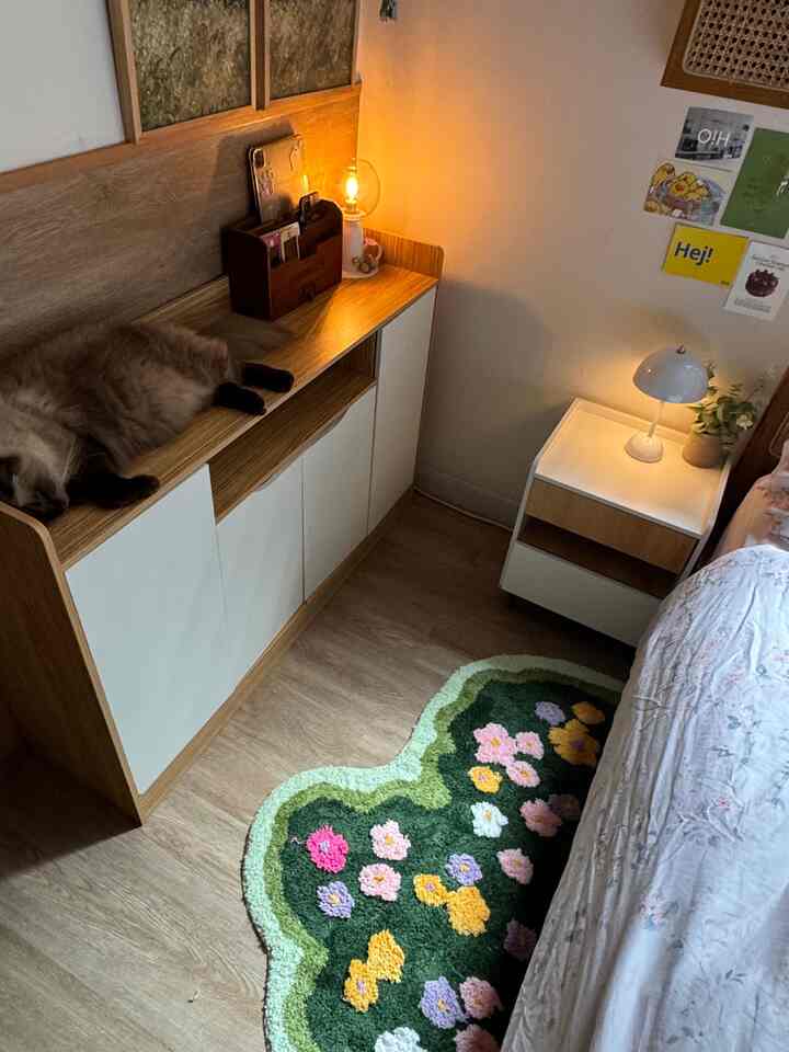 Wood tone and green-themed bedroom featuring a floral rug and a pet cat, creating a cozy and warm atmosphere