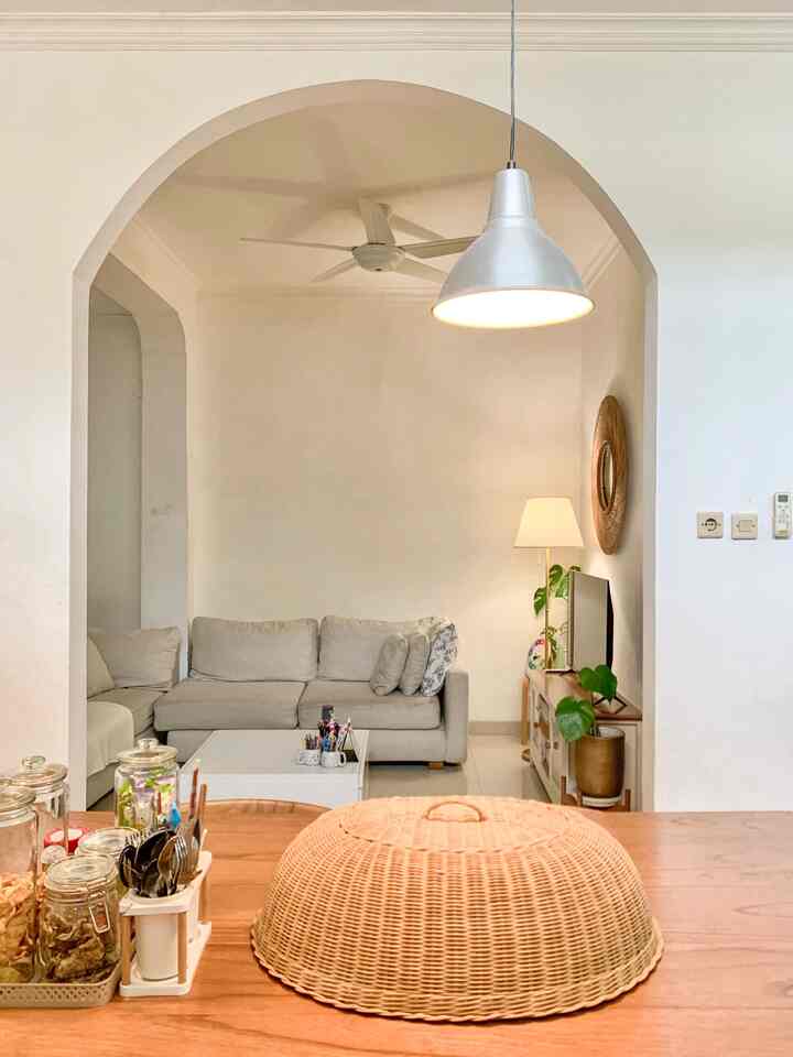 Warm white tones and natural wood blend in a living room space featuring an arched doorway and a comfortable sofa for a cozy interior