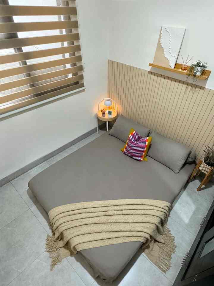 Beige and gray toned bedroom featuring a bed and table lamp with a cozy, clean atmosphere