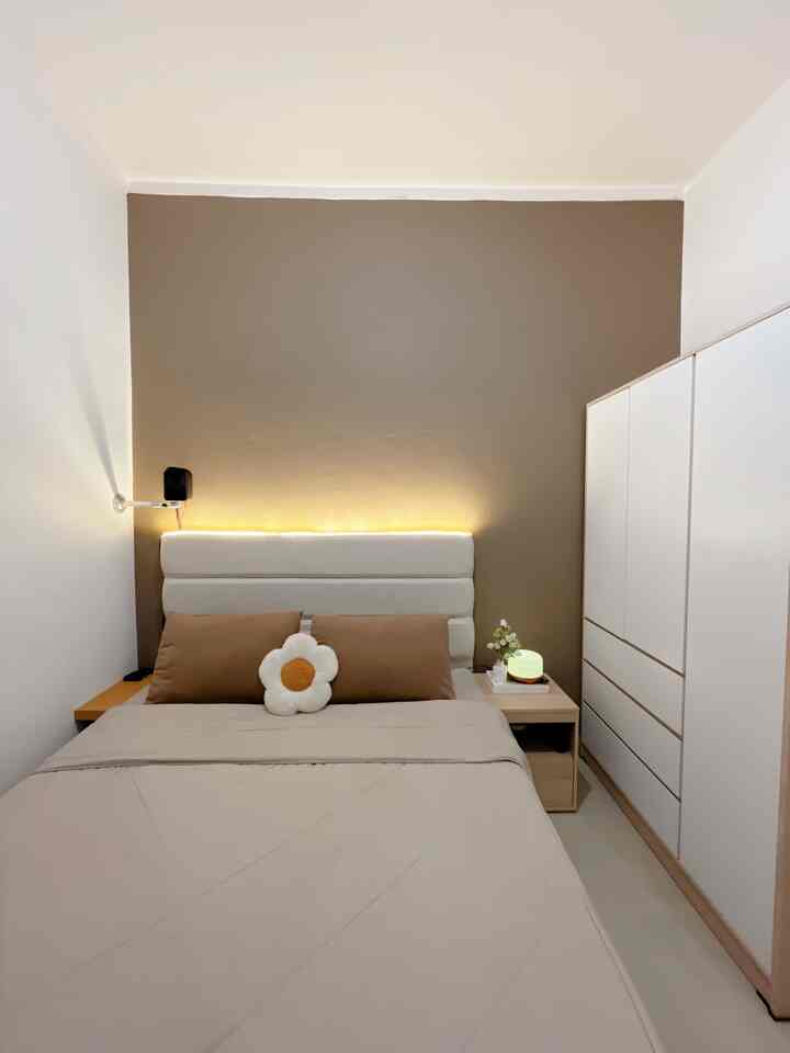 Beige and white toned bedroom featuring a bed with beige bedding centered and a white wardrobe on the right, creating a clean space