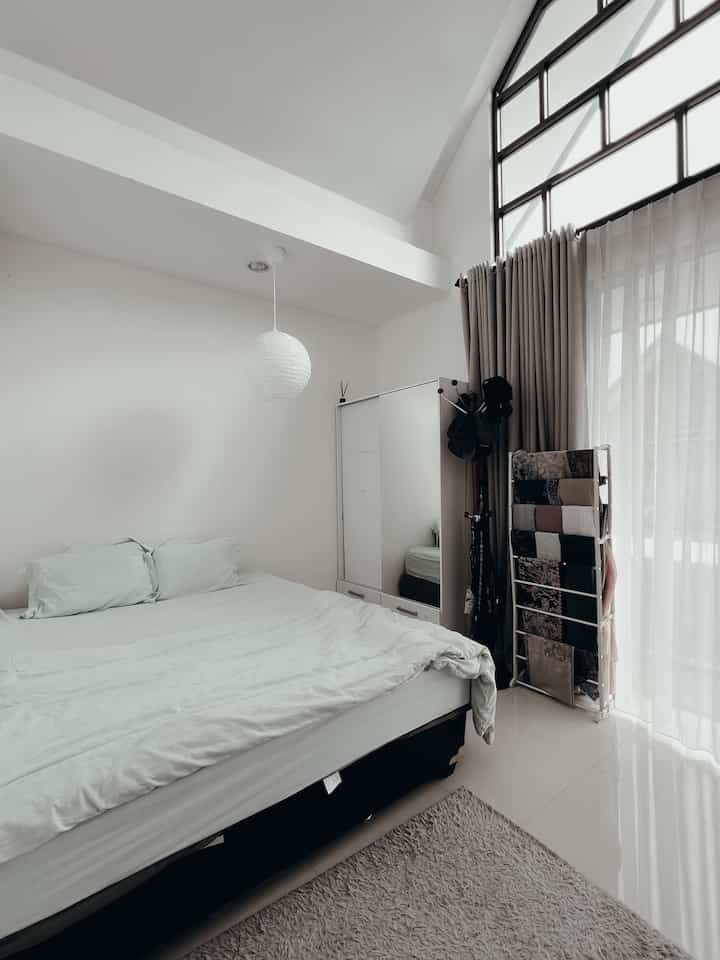 Neutral white and beige bedroom featuring a large bed, wardrobe, and soft natural lighting creating a calm atmosphere