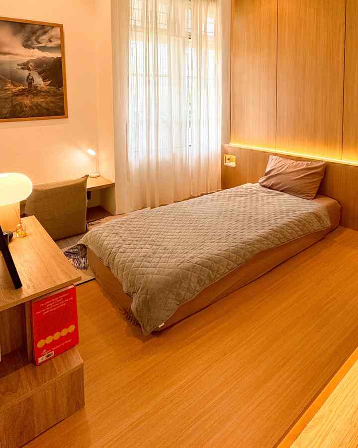 Warm wood-tone bedroom for single occupant featuring a bed, desk, and storage with cozy natural lighting