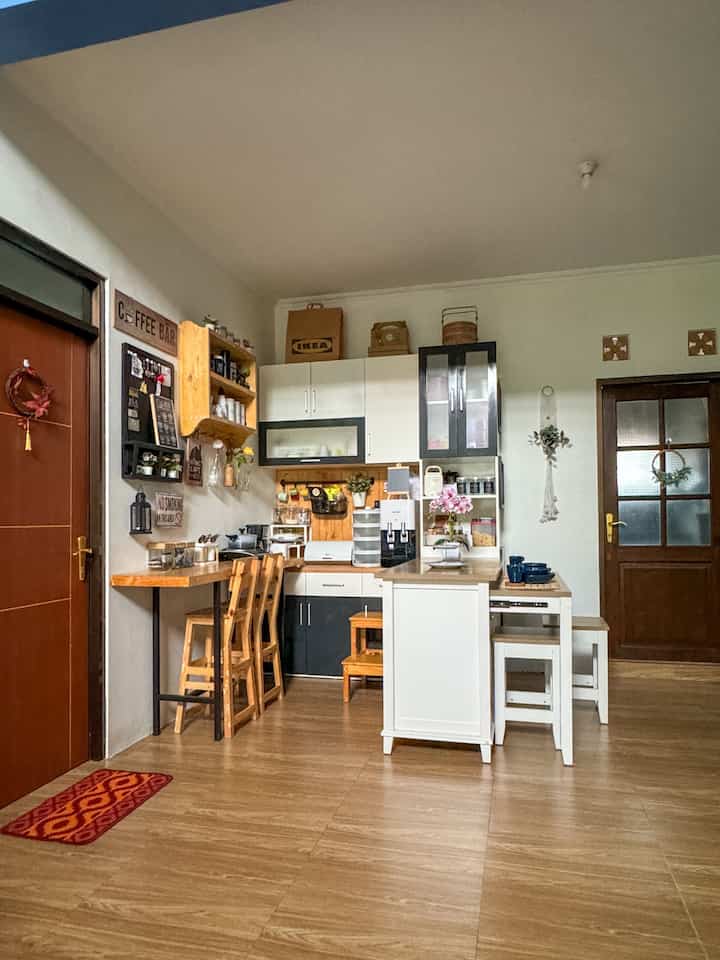 Natural wood tone and white kitchen creating a cozy cafe style space with bar stools and coffee-related decor in a compact kitchen setting