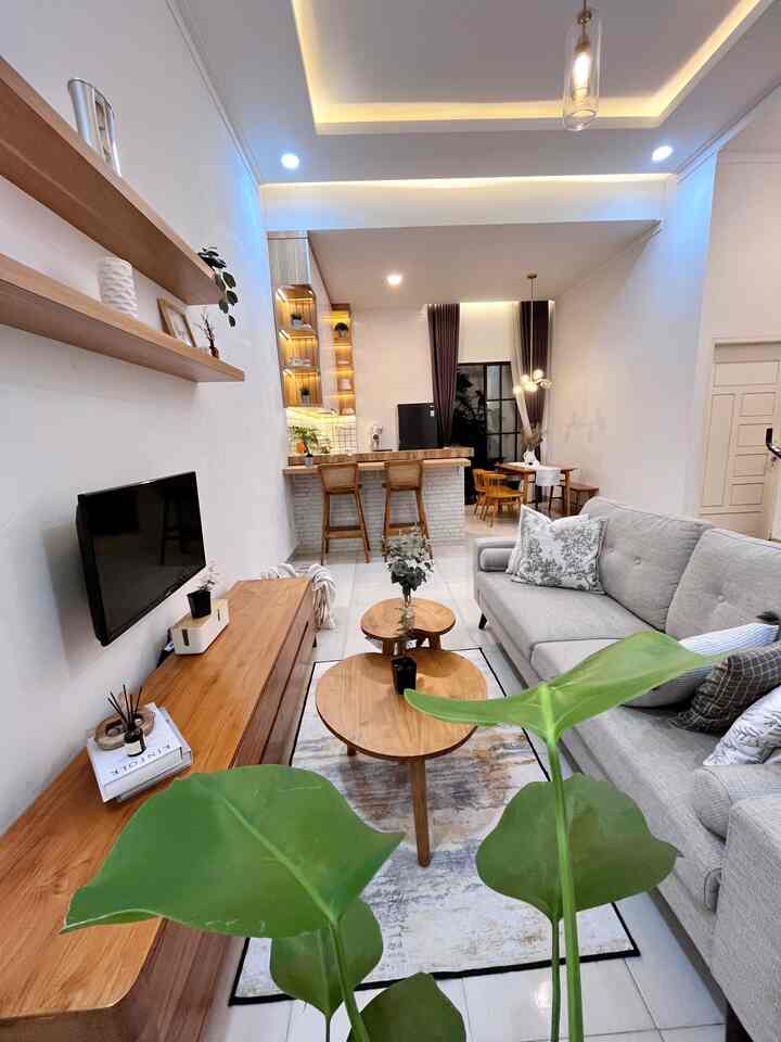 Natural brown and white toned open living room and kitchen space featuring wooden furniture and gray sofa with cozy modern atmosphere