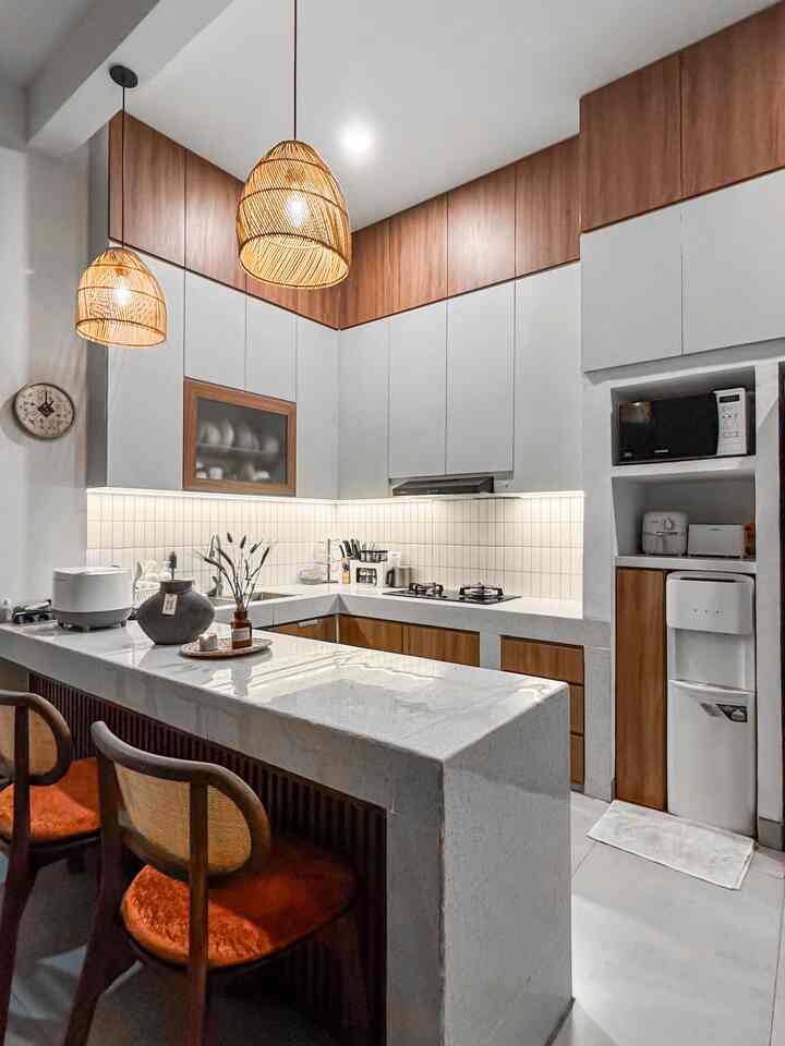 Modern kitchen featuring white and wood tones, marble kitchen island, and rattan pendant lighting creating a warm atmosphere