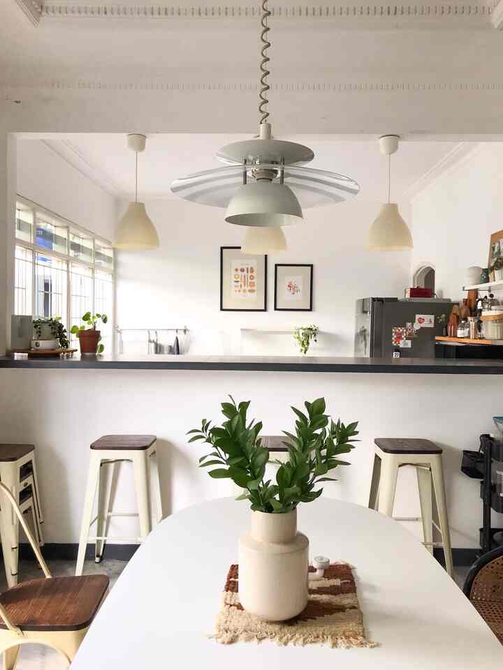 Modern natural dining room in white and beige tones featuring a dining table, bar stools, and pendant lights