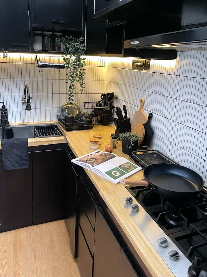 Compact kitchen with wood tones and black cabinetry, featuring storage ideas and neatly organized kitchen utensils