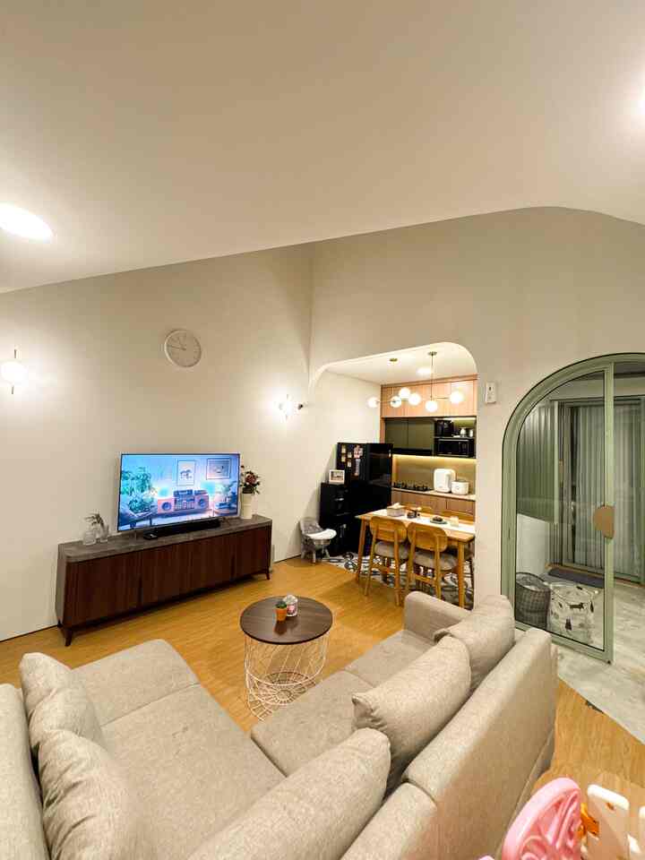 Natural tones with white walls in a living room and kitchen space, featuring beige sectional sofa and wooden dining table in a simple, cozy interior