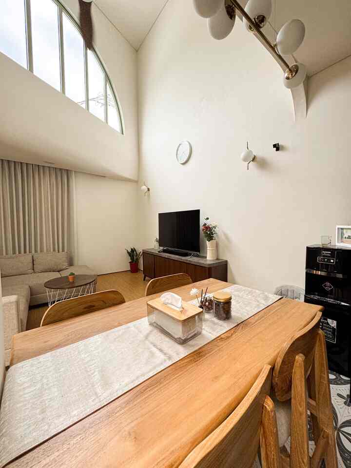 Bright white and wood tone living and dining room featuring a wooden dining table and beige sofa in a warm modern space