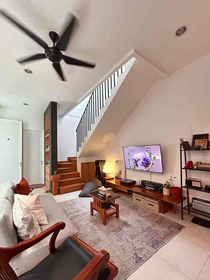 Living room with white walls and wood-tone furniture featuring a 3-seater sofa, armchair, and abstract patterned carpet creating a cozy atmosphere
