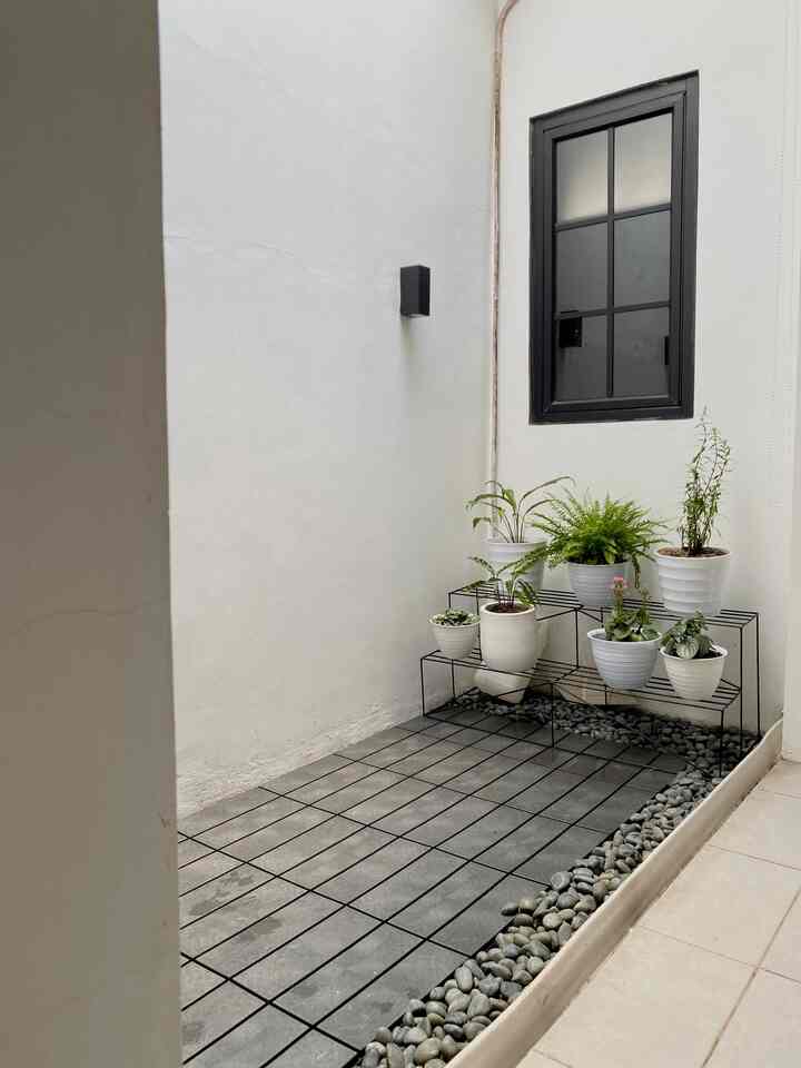 White and gray tone balcony with wall sconce and multiple potted plants in a clean setting